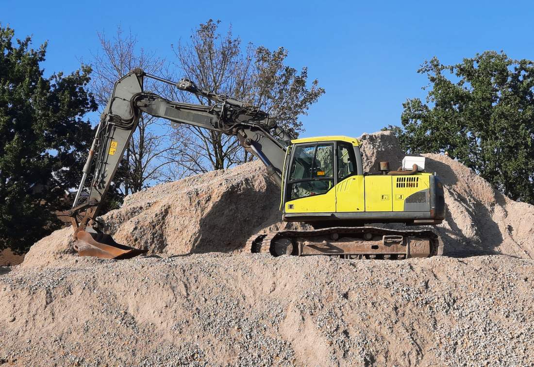 Licensed stock photograph: a tracked excavator standing on a worked pile of earth and rock.
